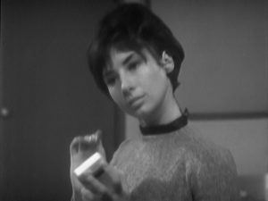 Susan Foreman, a teenage girl with short black hair. She listens to a song on a portable transistor radio that she holds in one hand.