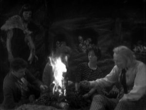 In a cave, Ian, Barbara, Susan and the Doctor sit huddled around a fire. Za, a caveman, stands over them, looking forlorn. They ignore him.